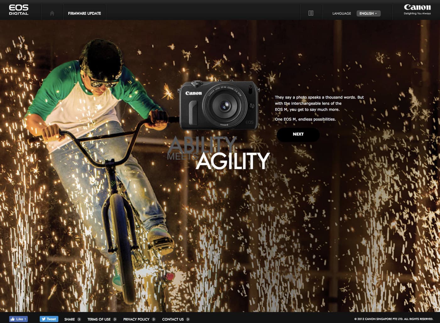 The EOS M campaign screen: a BMX rider riding through a shower of sparks, the camera body floating over the photograph, and the line 'They say a photo speaks a thousand words. But with the interchangeable lens of the EOS M, you get to say much more.'